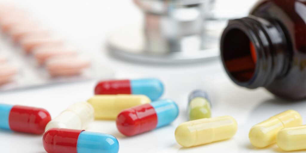 Colorful capsules and pills scattered beside an open prescription bottle.