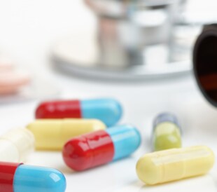 Colorful capsules and pills scattered beside an open prescription bottle.