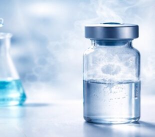 Sealed vial with vapor above liquid, laboratory glassware blurred in background.