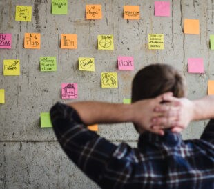 A founder looks at a wall of post-it notes