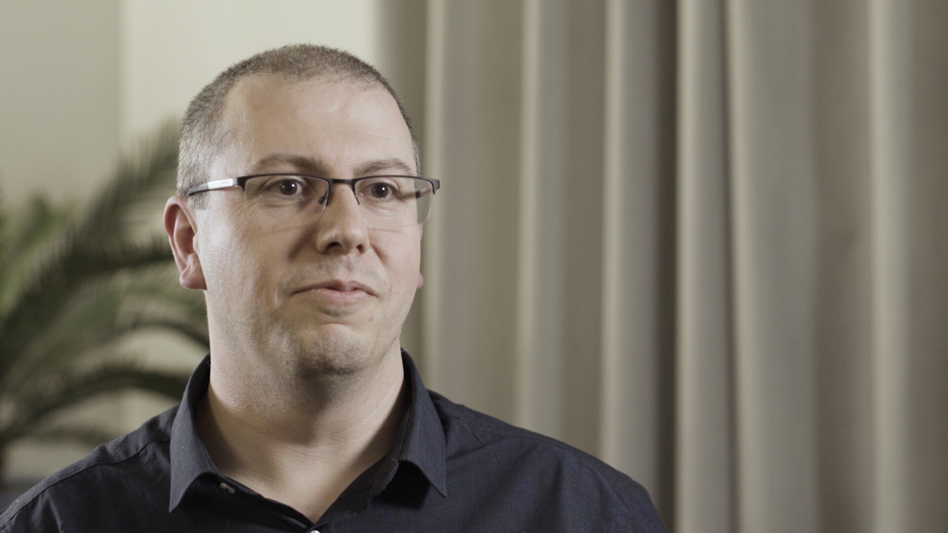 Darren Roberts, a man in glasses who who studies cancer transcriptomics and radiobiology, looks at the camera