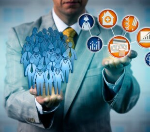 A graphic of a person in a suit holding many human figures and icons representing health in their hands, demonstrating the impact of Genotype-phenotype research databases