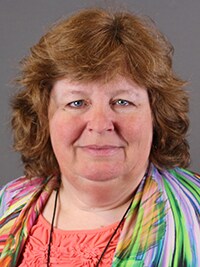 Marcia Slater, qPCR expert, has reddish hair and is wearing a red shirt and a rainbow cardigan