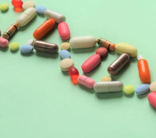 A variety of pills laid out to form a double helix on a green background