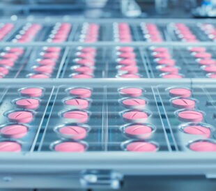 Macro Shot of Pink Pills During Production and Packing Process on Modern Pharmaceutical Factory. Medical Drug Manufacturing.