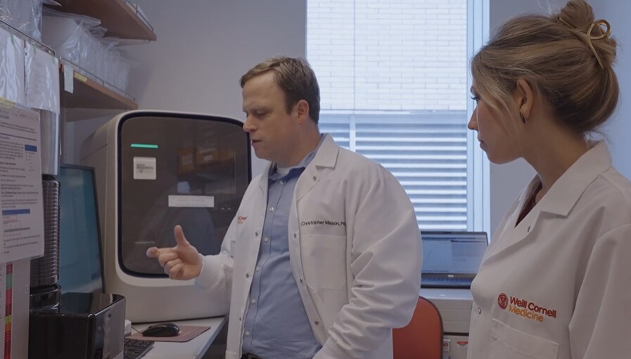 Dr. Christopher Mason of Weill Cornell Medicine discussing qPCR workflow with a colleague in a molecular diagnostics lab.