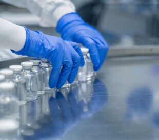 Detail of hands working in pharmaceutical factory manufacturing sterile bottles