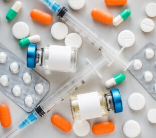 Syringes, injection bottles and tablets lying on the table. Close-up, indoors, view from above. Day light, studio photo. Healthcare concept