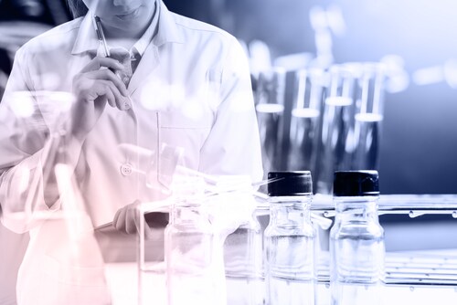 Scientist writing a report with lab equipment in foreground. Image: Looker_Studio/Shutterstock.com