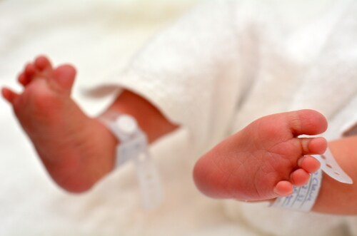 Newborn baby feet with identification tags. Image: ChameleonsEye/Shutterstock.com