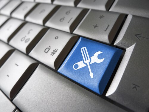 Assistance and computer service concept with toolkit icons and symbol on a blue laptop computer key for website and online business. Image: niroworld/Shutterstock.com.