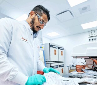 Researcher studying paper on a lab bench