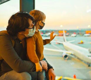 Masked family at airport watching planes