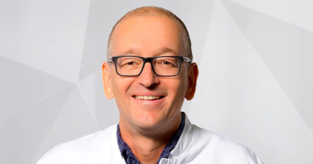 A man smiling and wearing glasses