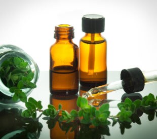 Essential oil bottles with fresh oregano leaves