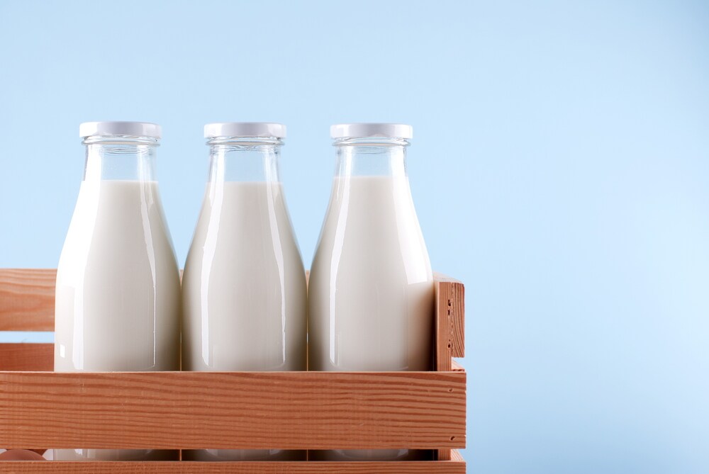 Three glass milk bottles in a wooden crate on a blue background