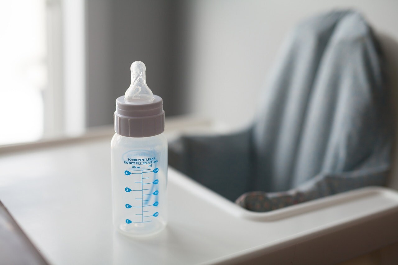 An empty baby bottle waits on a high chair, symbolizing the importance of food safety testing for Cronobacter in powdered infant formula