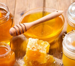 various types of honey in glass jars on a wooden table