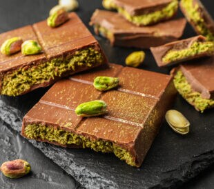 Pieces of Dubai chocolate bars with pistachios and knafeh on grey table, closeup