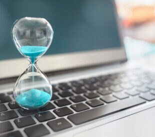 Hourglass on laptop computer concept for time management and countdown to deadline