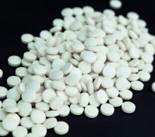 Heap of white pills on a black background.