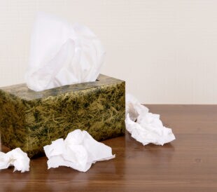 Box of tissues on a wood table (the background is cream pattern wallpaper).
