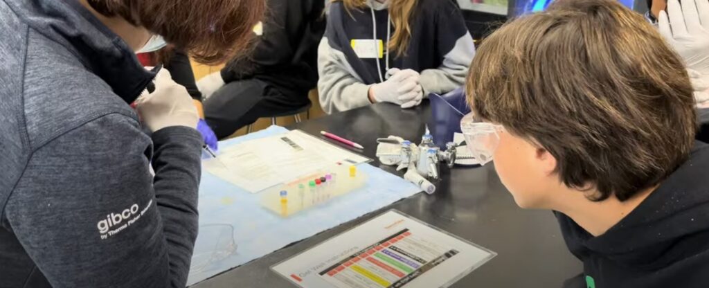 Thermo Fisher Scientific volunteers demonstrate a gel electrophoresis lab to identify DNA. 