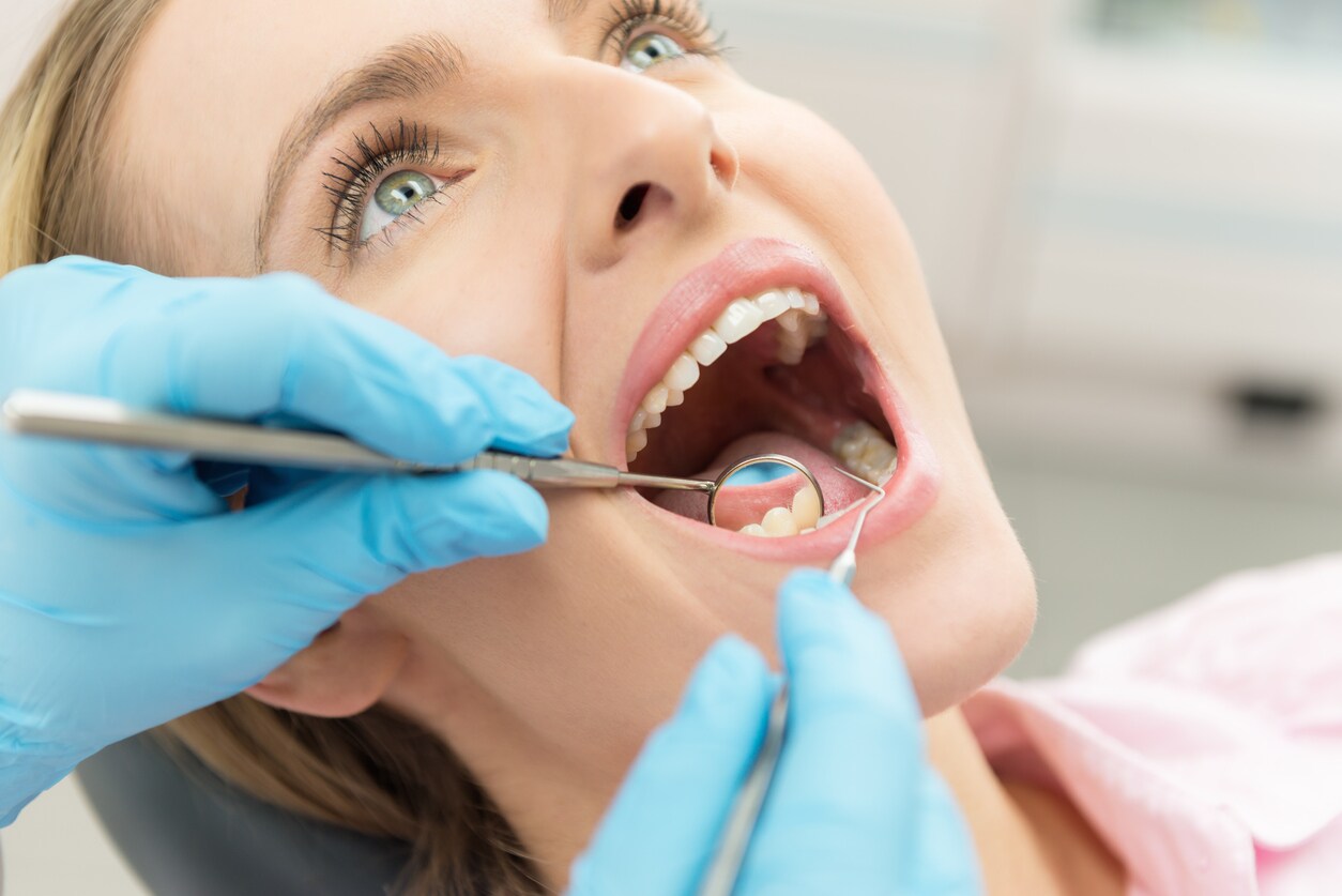 Dentist looking at a patient's teeth following dental crown procedure Dentist looking at a patient's teeth following dental crown procedure