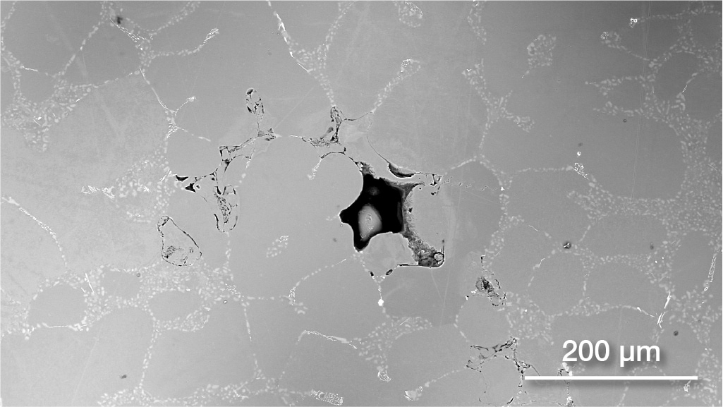 SEM image of aluminum sample with pores and oxides highlighted.