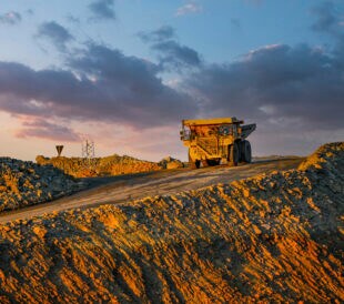 A large haul truck captured under the warm glow of sunset at a mining site, showcasing industrial activity