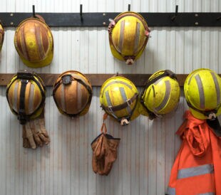 Safety helmets and gloves hang from a rack on a mining site