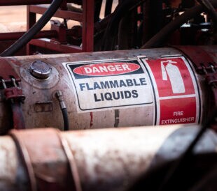 Flammable liquid (such as oil, fuel or hydraulic) container with standard caution sign on the body part. It's using in heavy industry and oil field operation.