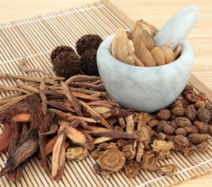 Chinese herbal medicine selection in a marble mortar with pestle and loose over bamboo mats. Image: marilyn barbone/Shutterstock.com.