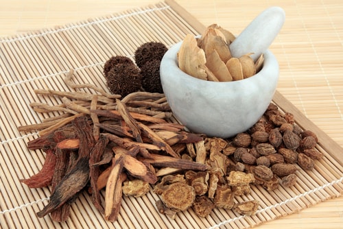 Chinese herbal medicine selection in a marble mortar with pestle and loose over bamboo mats. Image: marilyn barbone/Shutterstock.com.