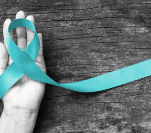 Teal ribbon awareness to support Ovarian Cancer PCOS on human hand with aging wood background: Symbolic concept for raising awareness/concerns/help and campaign on people living with illness. Image: Chinnapong/Shutterstock.com.