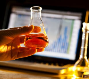 Scientist doing research and holding a beaker. Image: Brian Goodman/Shutterstock.com.