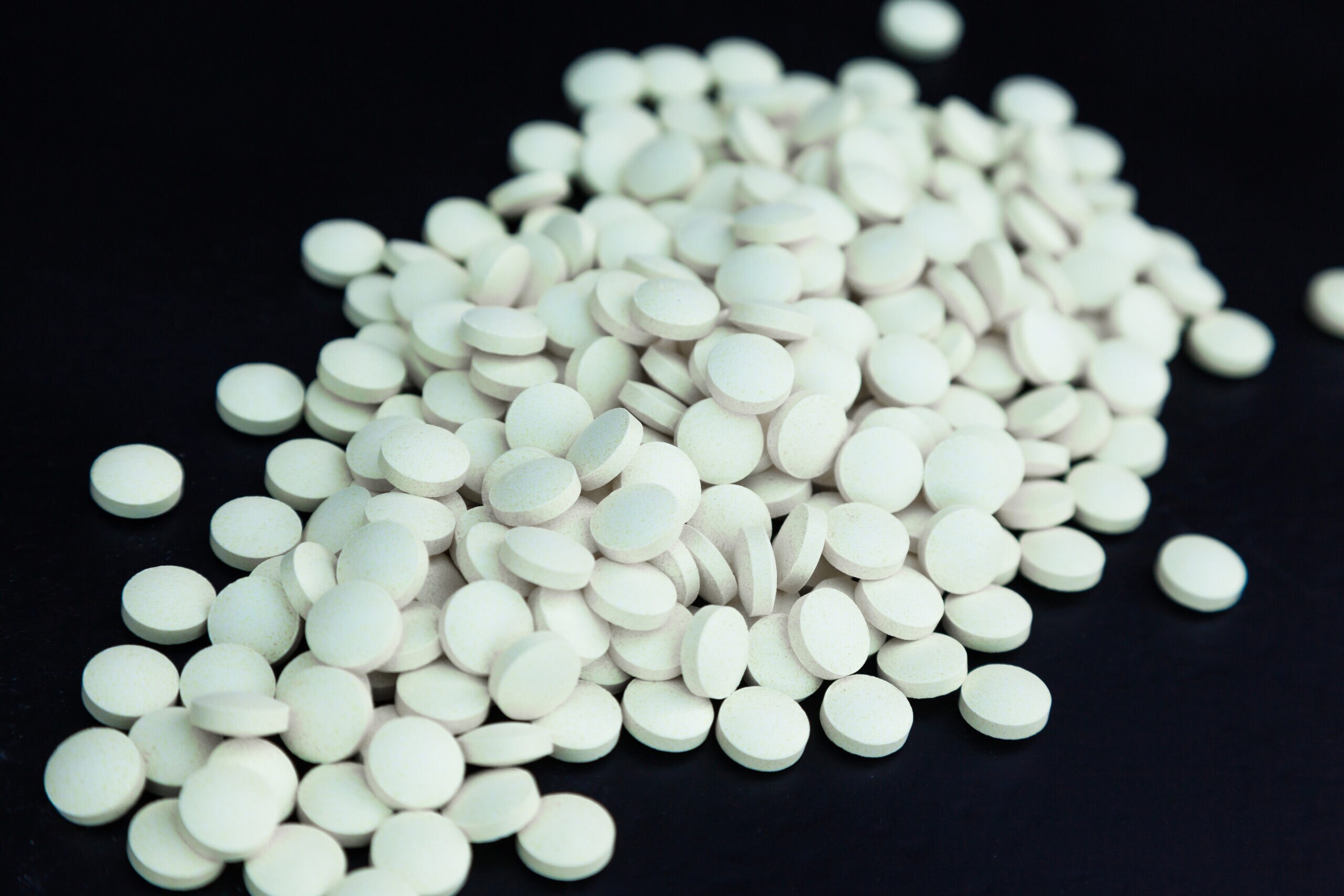 Heap of white pills on a black background.