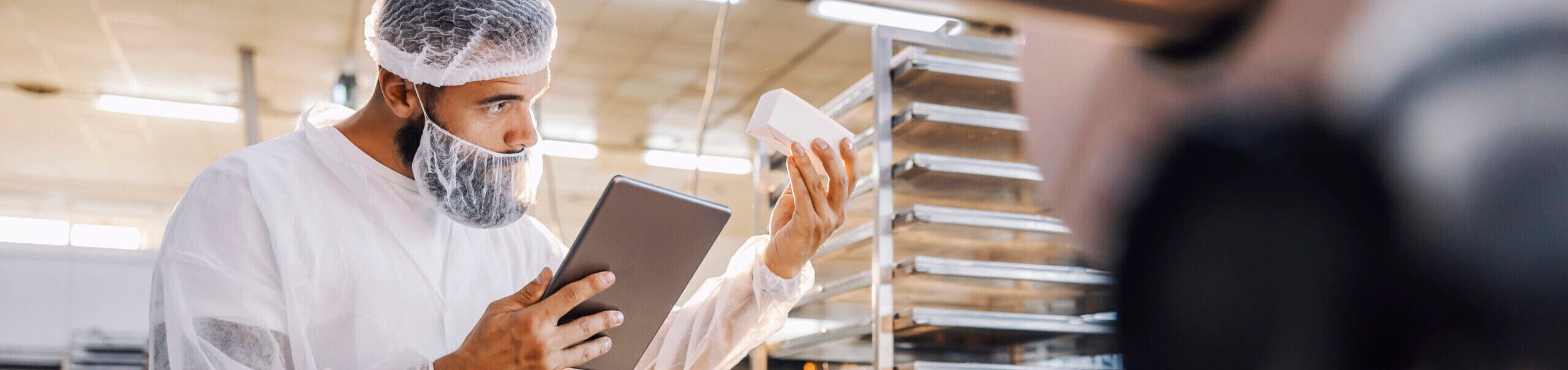 A food quality controller with tablet checking on cookies in the box.