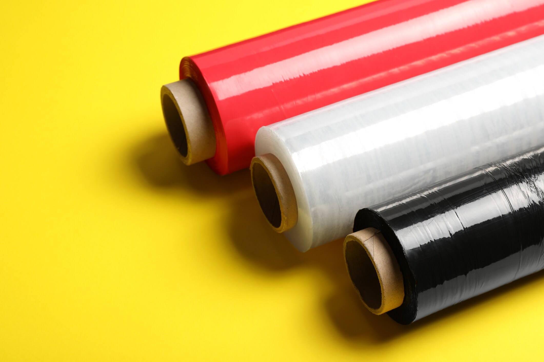 Different plastic stretch wrap films on yellow background.