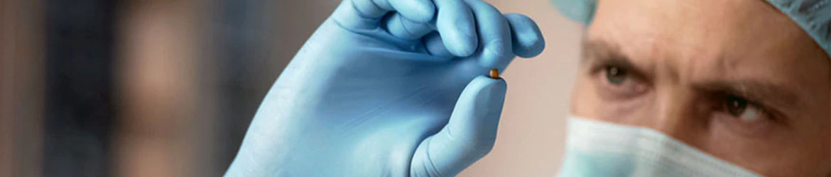 Scientist wearing mask and gloves Scientist inspects a small pellet