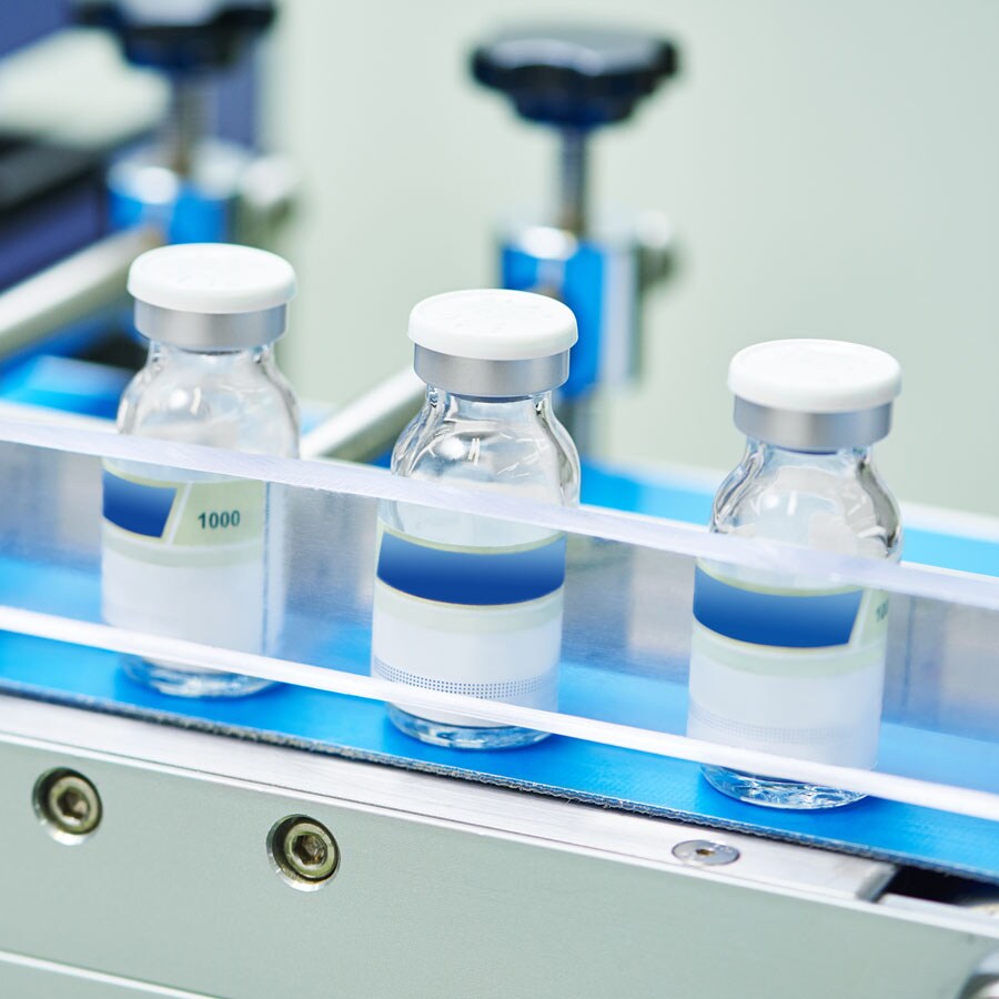 Vials on a conveyor belt Vials which will contain a drug are lined up to be filled