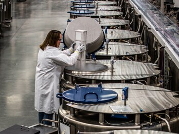 Global supply chain management services scientist picking up item from vat