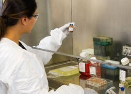 Cell & Gene Therapy Custom Services Female scientist inspects a small bottle in a work bench.