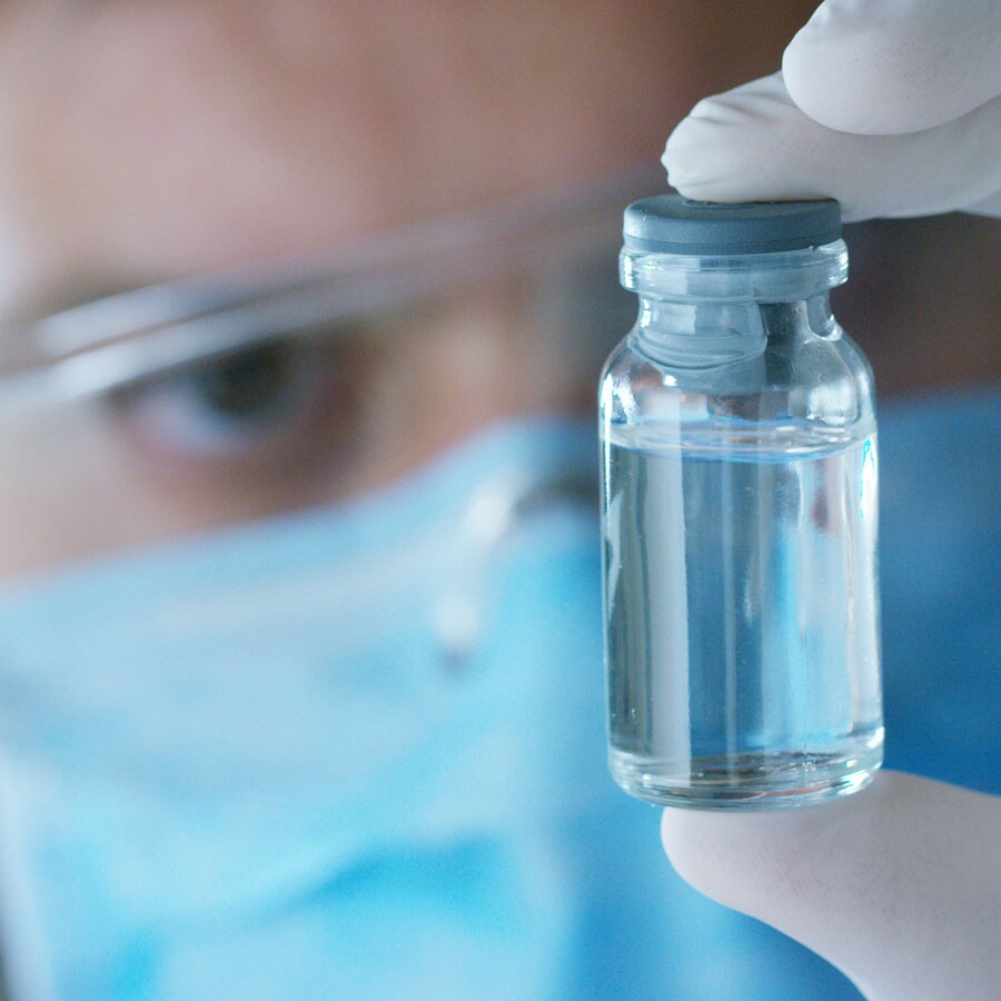 scientist looks at a vial scientist evaluating his solution and determining next steps