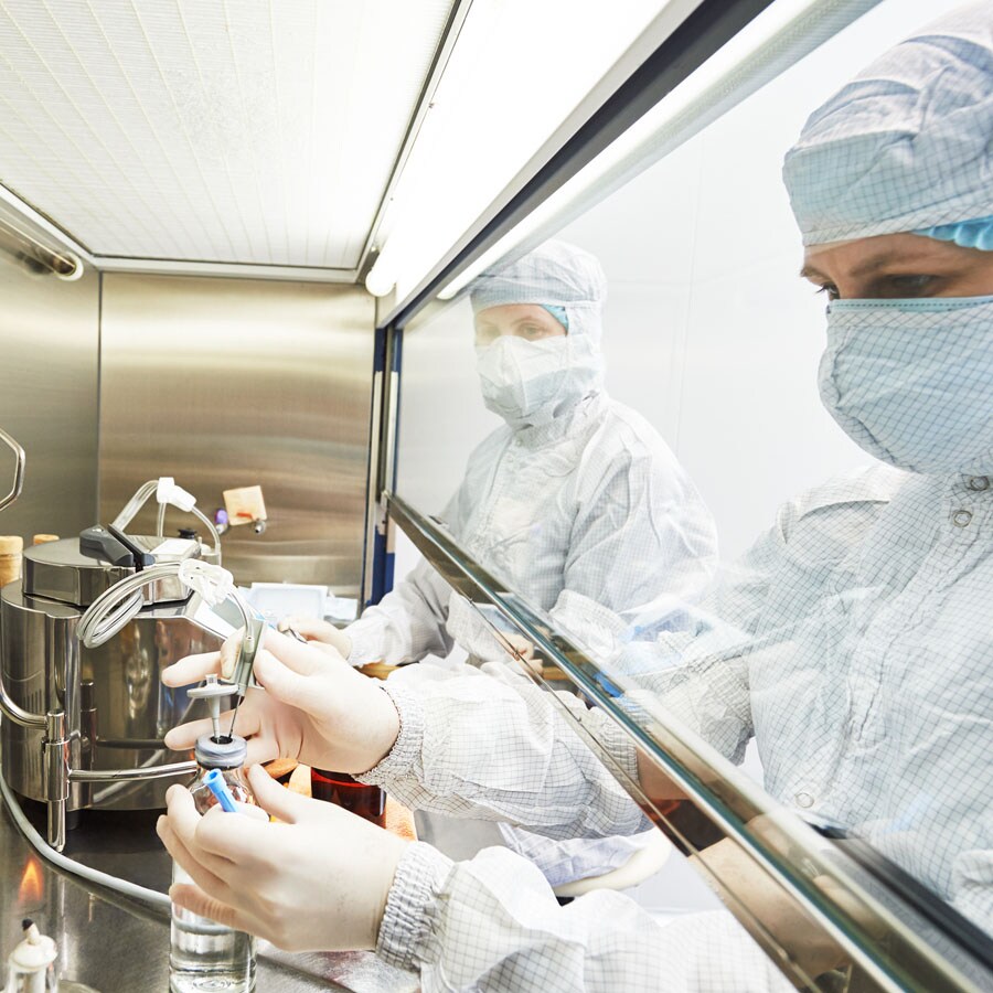 Scientist works with lab equipment in laminar flow hood Scientists wearing PPE works in a laminar flow cabinet protecting both sample and the researcher