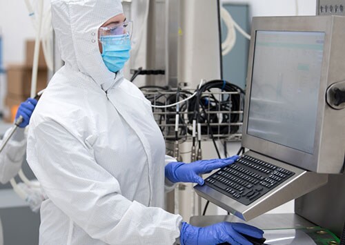 Scientist working on HyPerforma Single-Use Fermentor (S.U.F.) Two CGT manufacturing scientists wearing PPE operating a HyPerforma Single-Use Fermentor (S.U.F.)