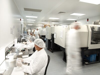 Gene editing services scientists doing bench work while multiple scientists walk around machinery in the background.