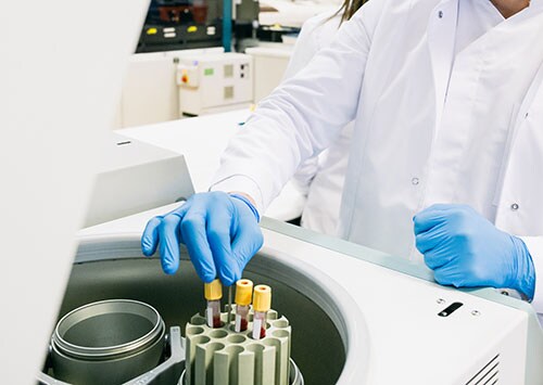 Scientist removing tubes from centrifuge in a lab Scientist removing tubes from centrifuge in a gene therapy research lab