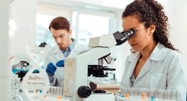Microscopy Decorative image of woman in lab coat looking through microscope
