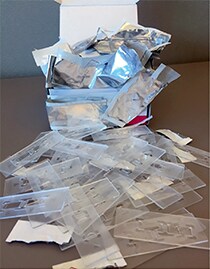 Waste generated from one box of 50 disposable slides Pile of used disposable slides and discarded slide packaging generated following 50 cell counting events